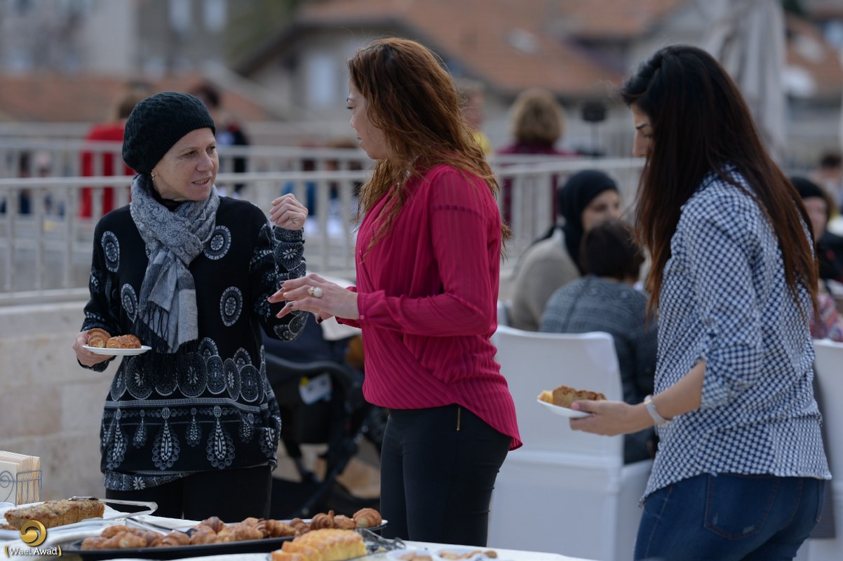 Women talking over food at an outdoor community gathering.