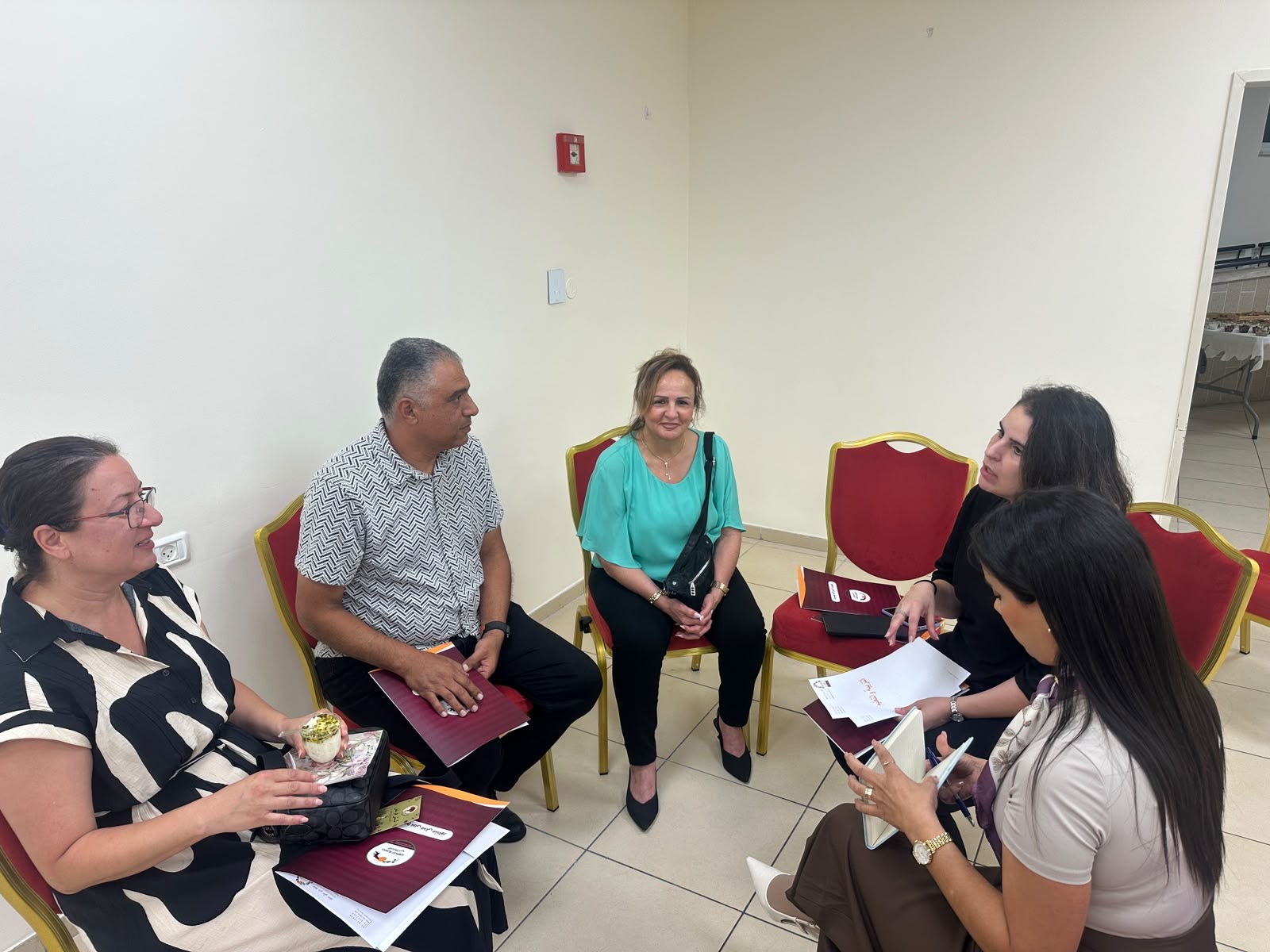 A small group of participants seated in a circle in conversation during the founding assembly, folders and papers in hand.
